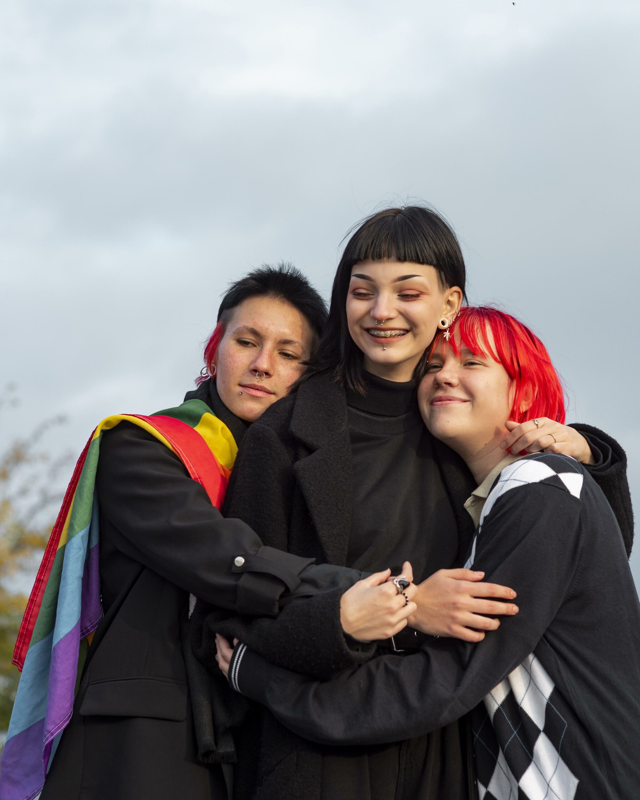 3 non binary people hugging each other.
