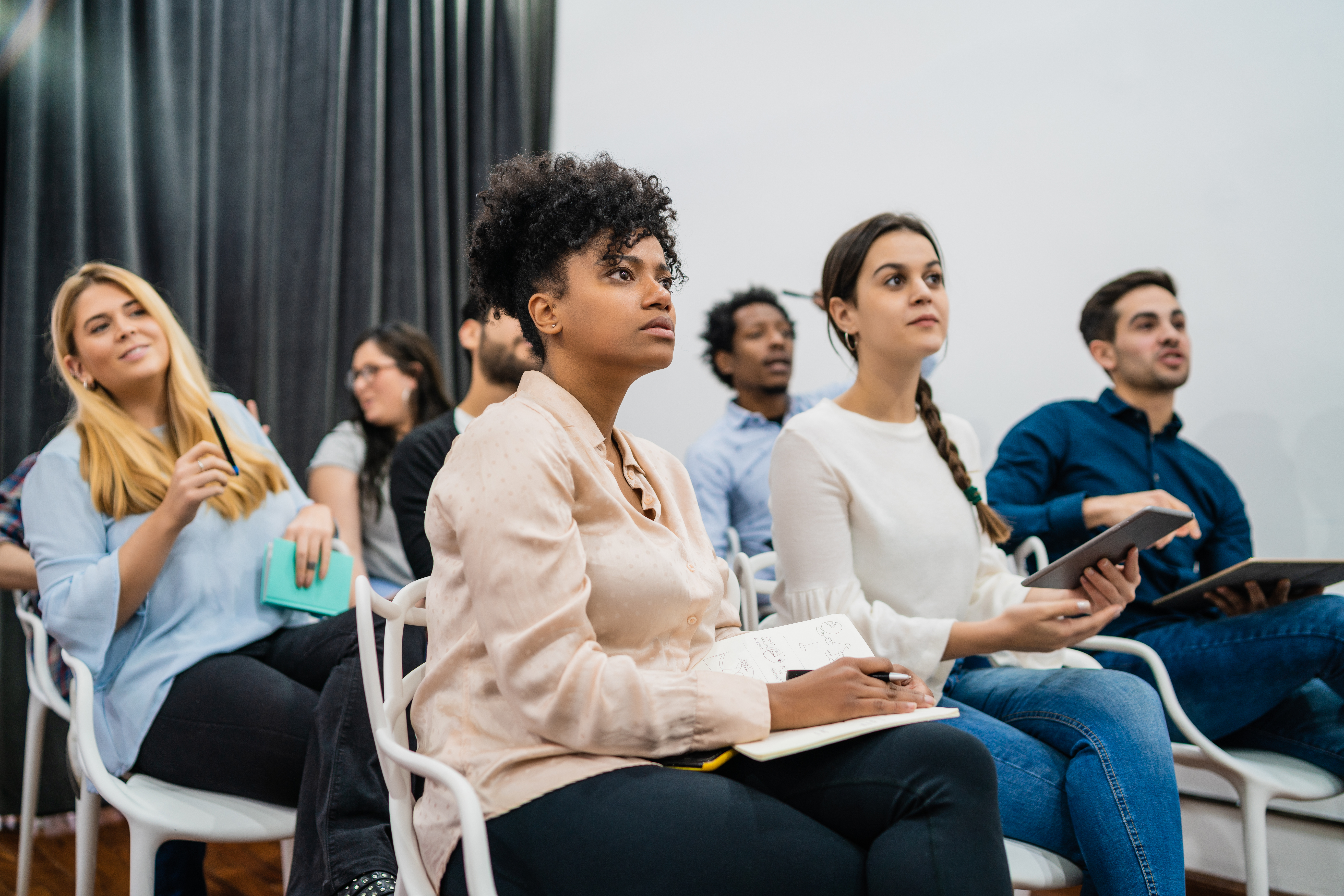 A group of people, sitting in chairs, listening to a presenter.