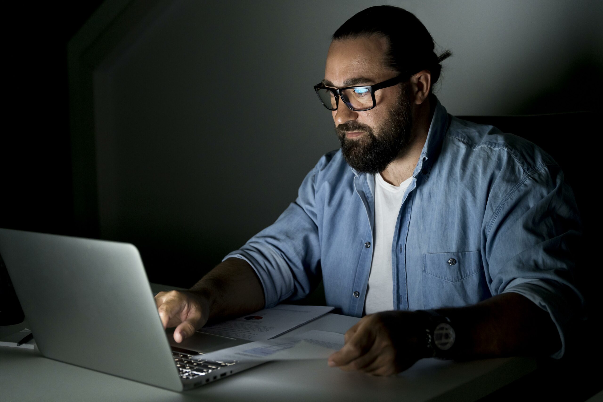 Person, in the dark, alone, working on their computer.