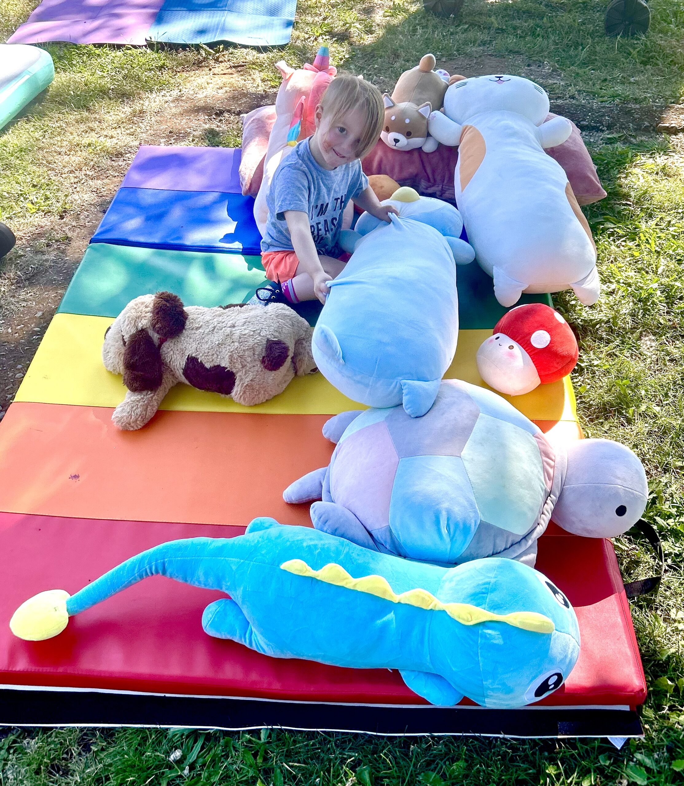 A young child playing with the collection of stuffed animals.