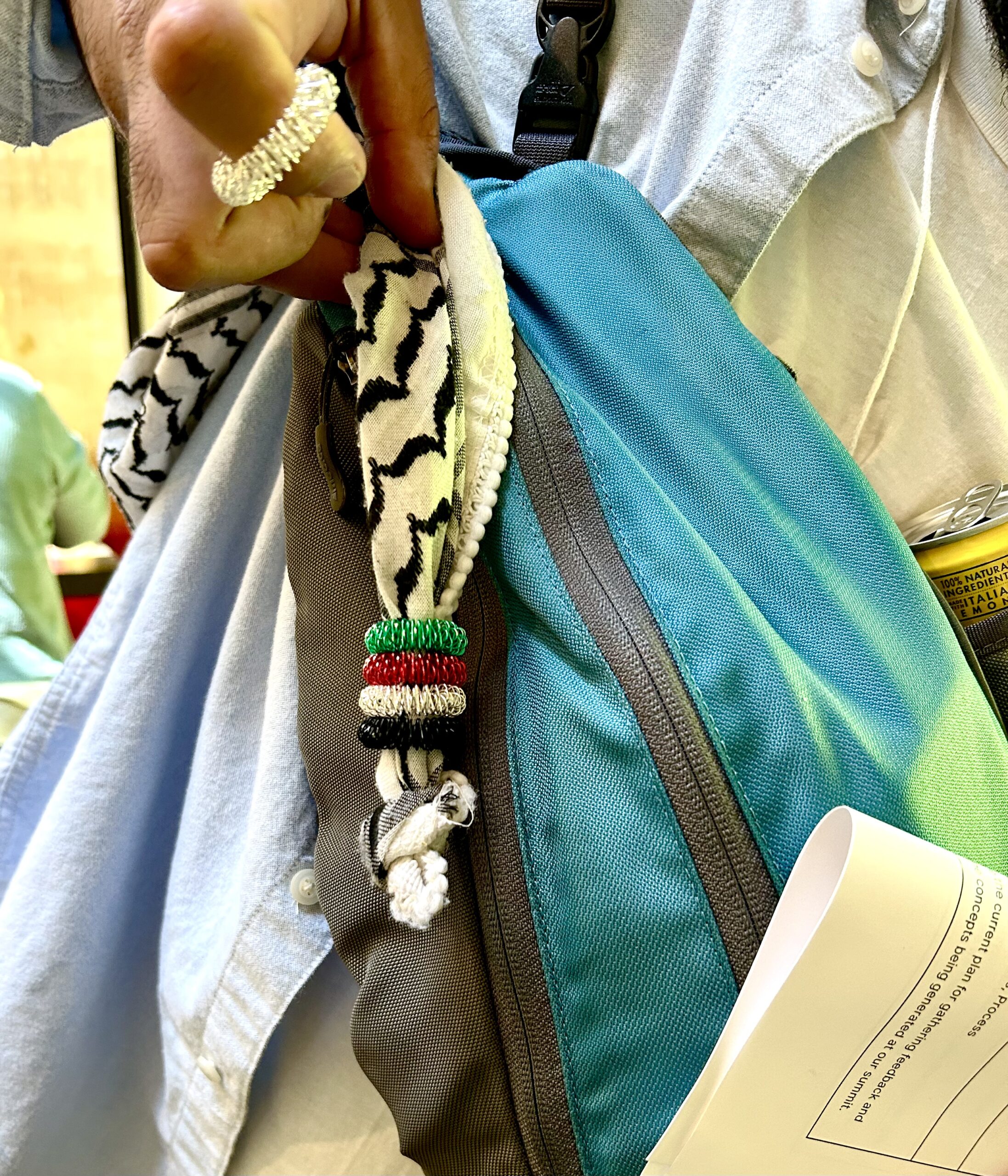 A Palestinian summit participant holds up a row of acupressure rings on the end of his Black and White Keffiyeh scarf.