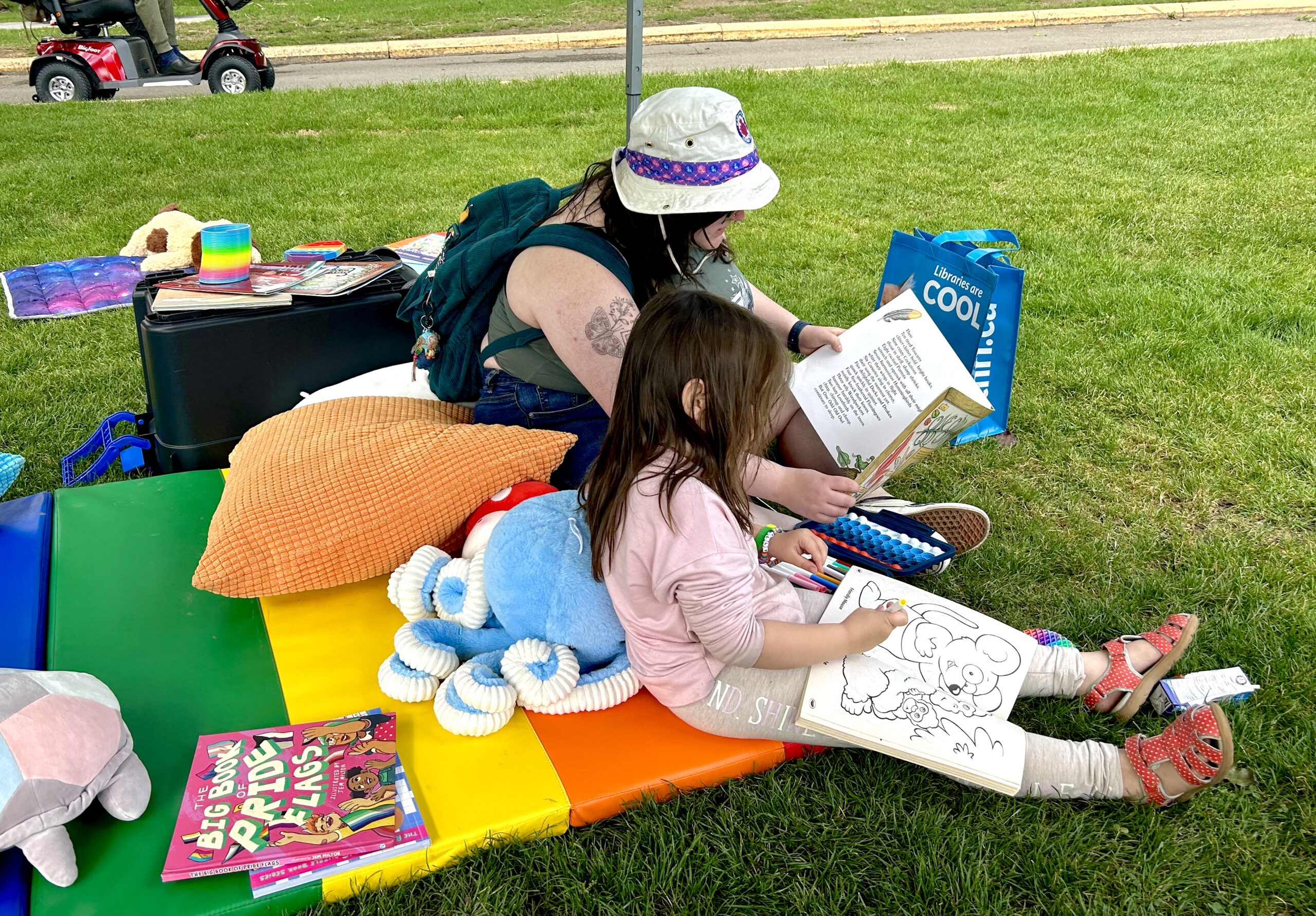 Parent reading to their child, as the child colours.