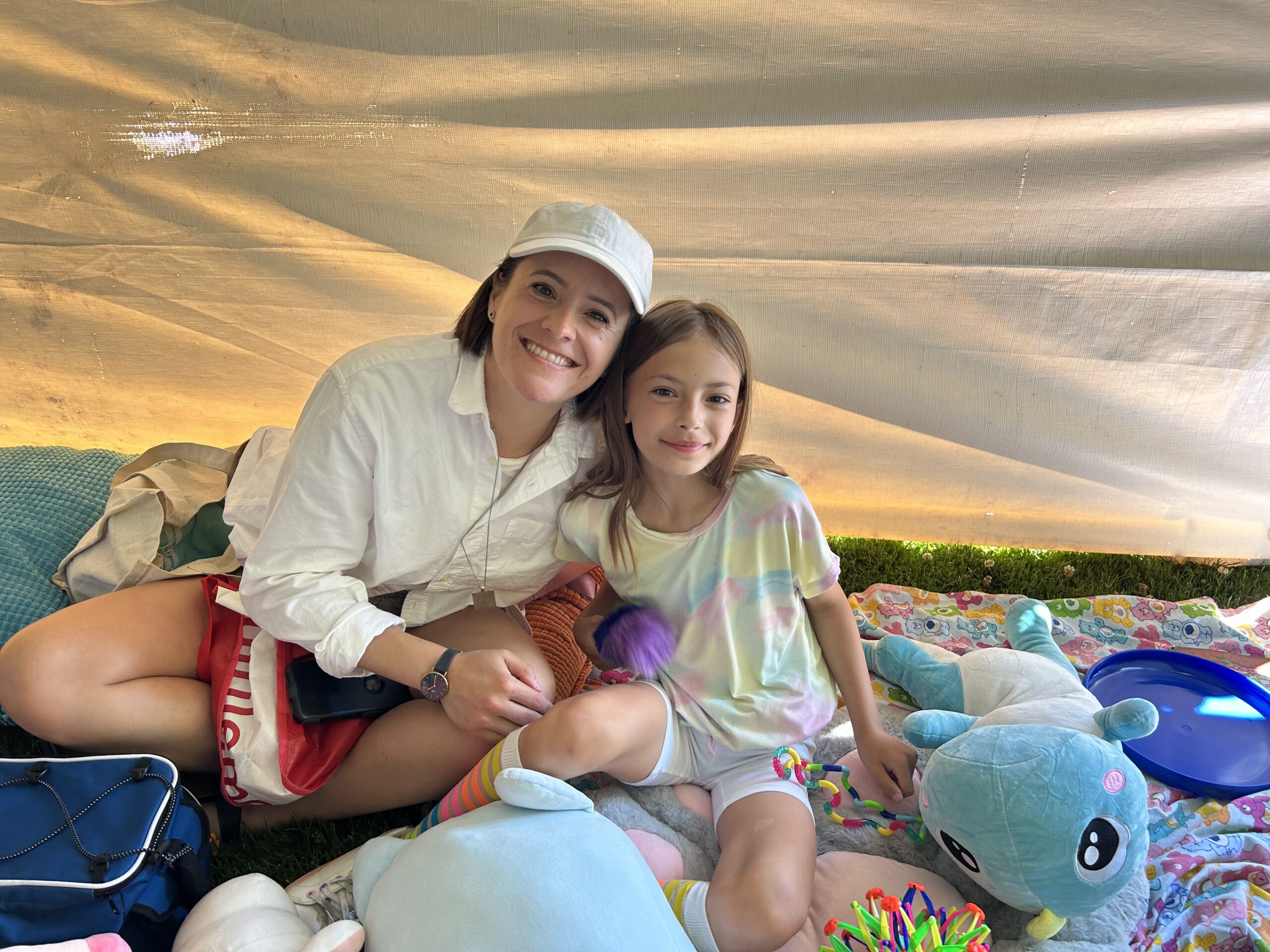 Parent and child sitting side by side on a blanket.