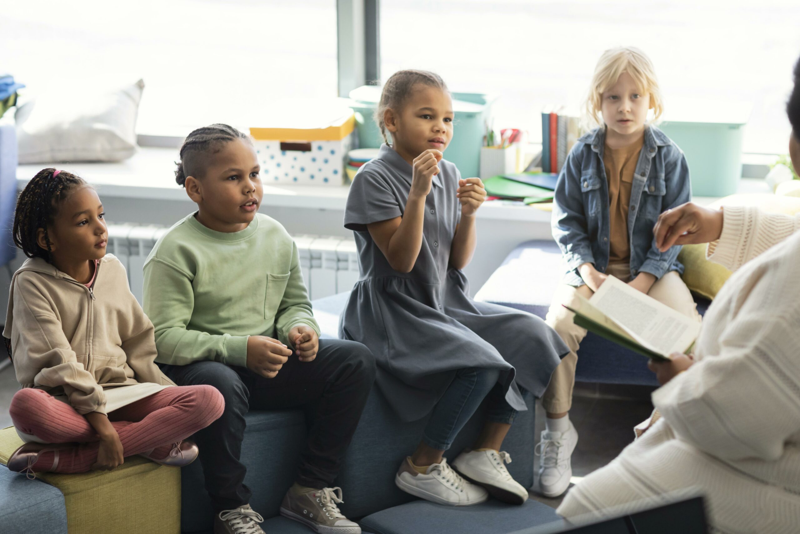 4 children listening to an adult with a binder.